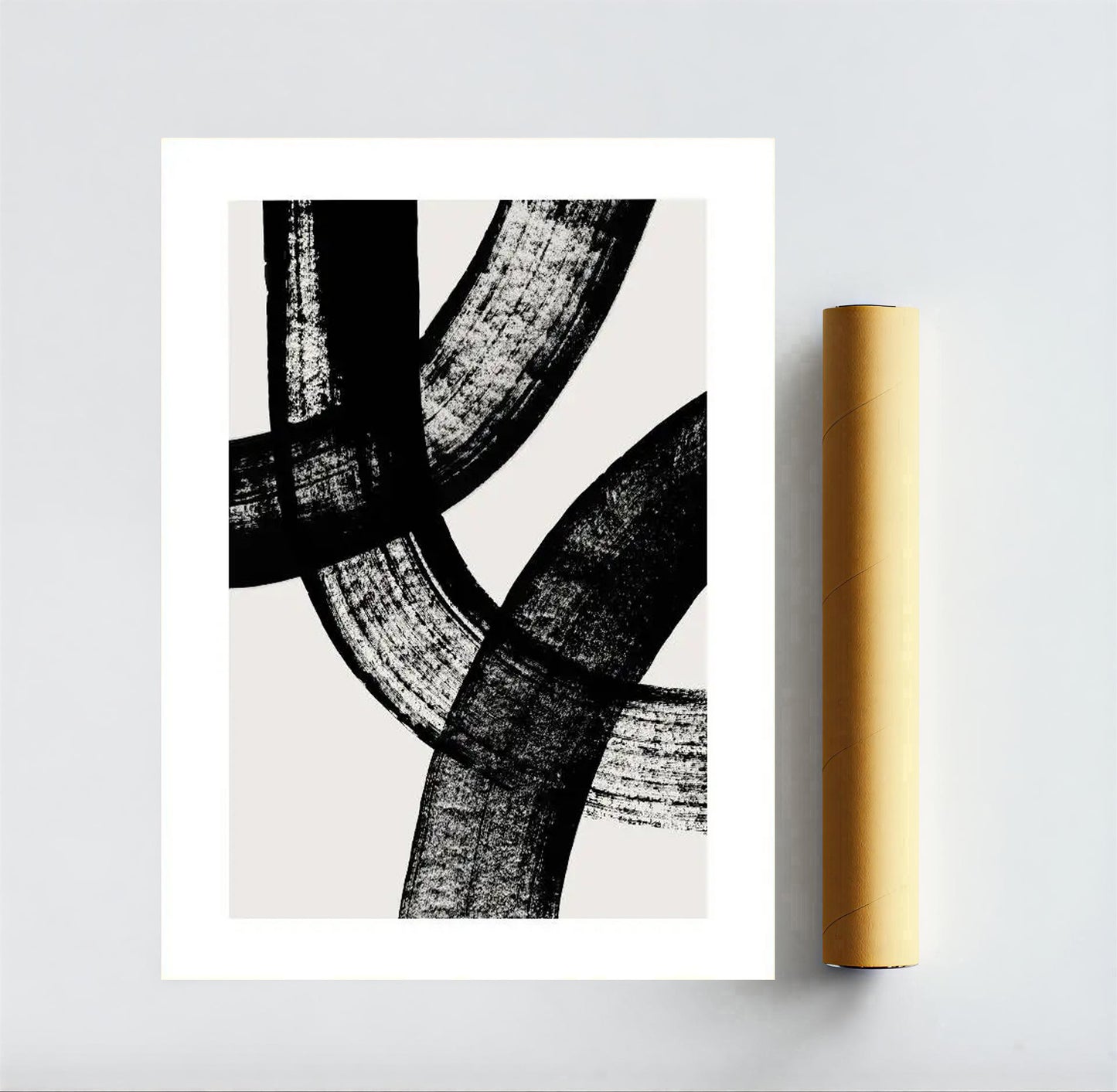 Abstract black and white art print on a gray background with a gold roll of paper.