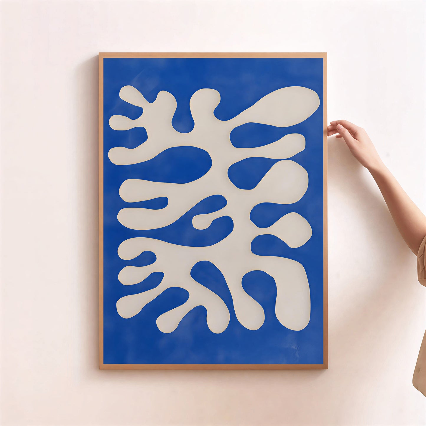 Framed abstract artwork with blue and white design on a light pink wall.