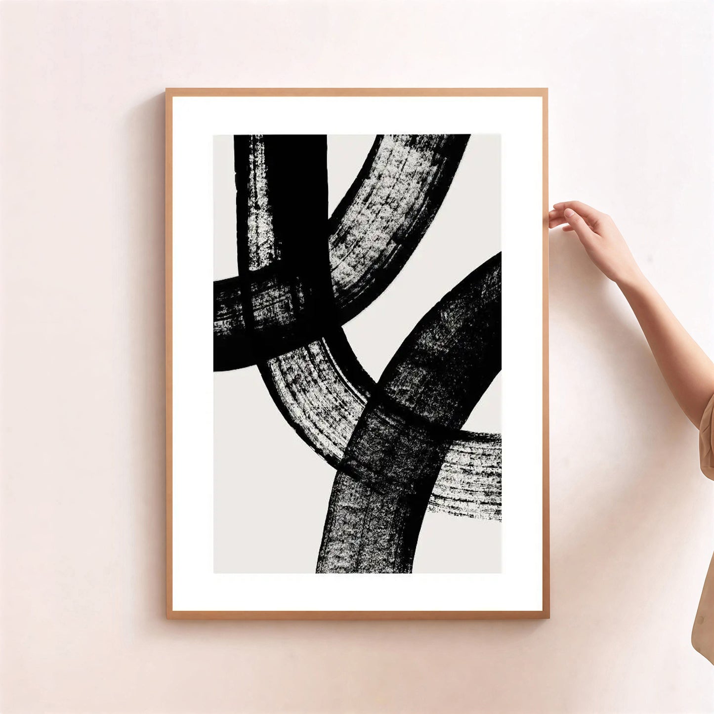 Framed abstract art print with black brush strokes on a white background, held by a person.
