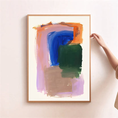 Abstract art print with colorful brush strokes in a wooden frame on a light pink wall.