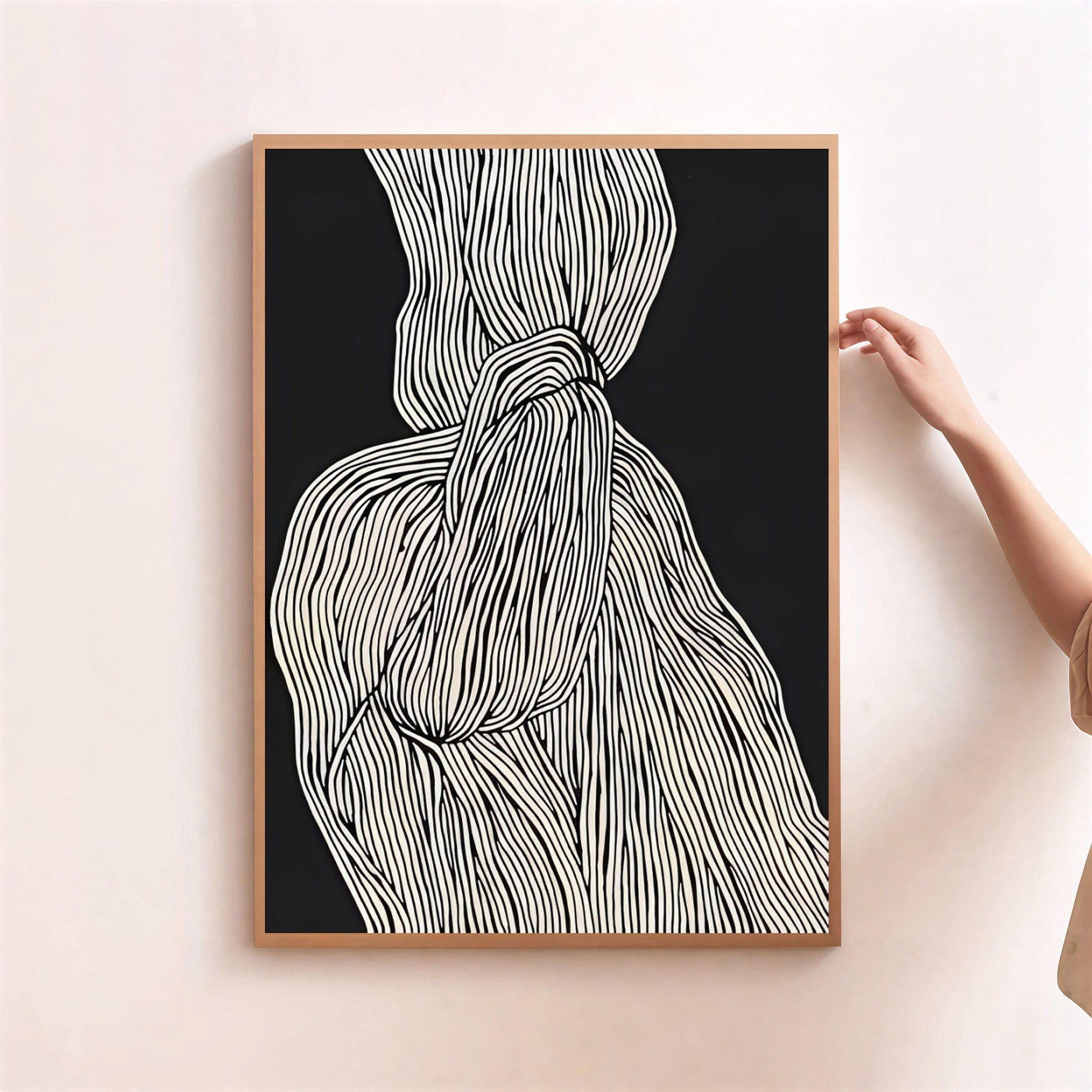 Framed abstract art print with a black background and white lines, held by a person.