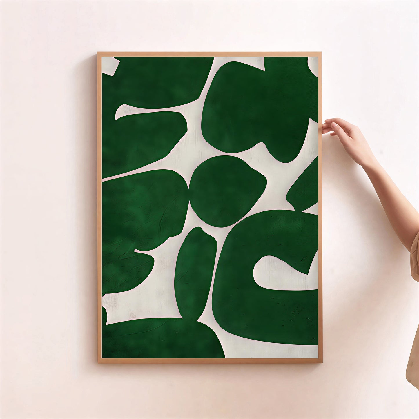 Framed artwork with green leaf pattern on a light pink wall