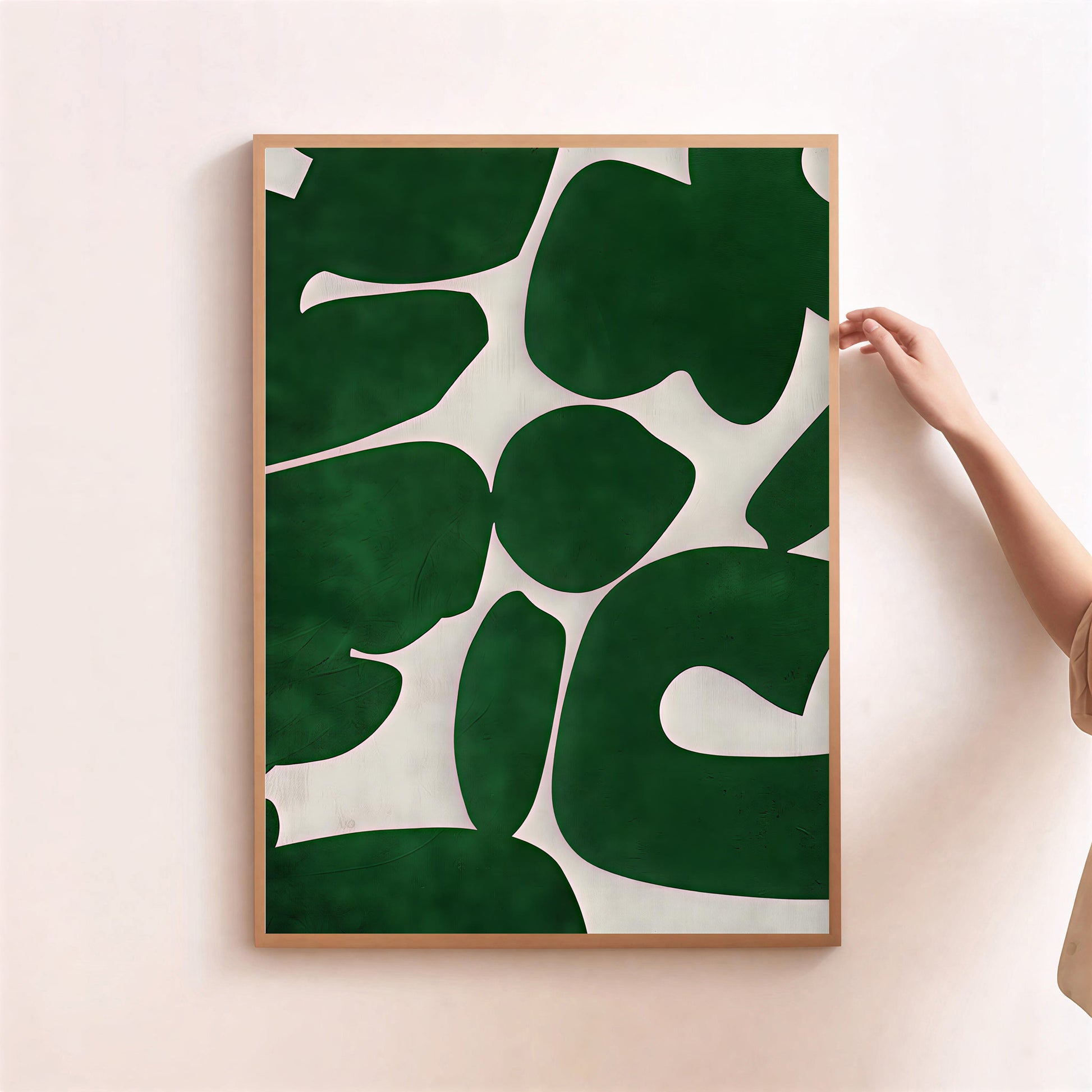 Framed artwork with green leaf pattern on a light pink wall
