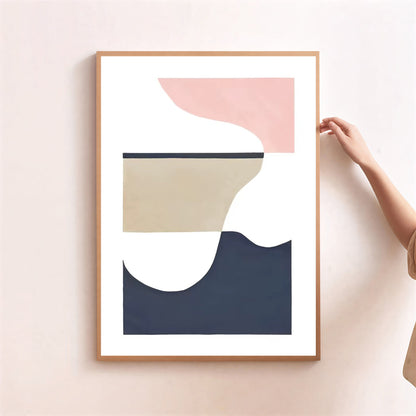 Abstract art print with geometric shapes in pink, beige, and navy on a light pink wall.