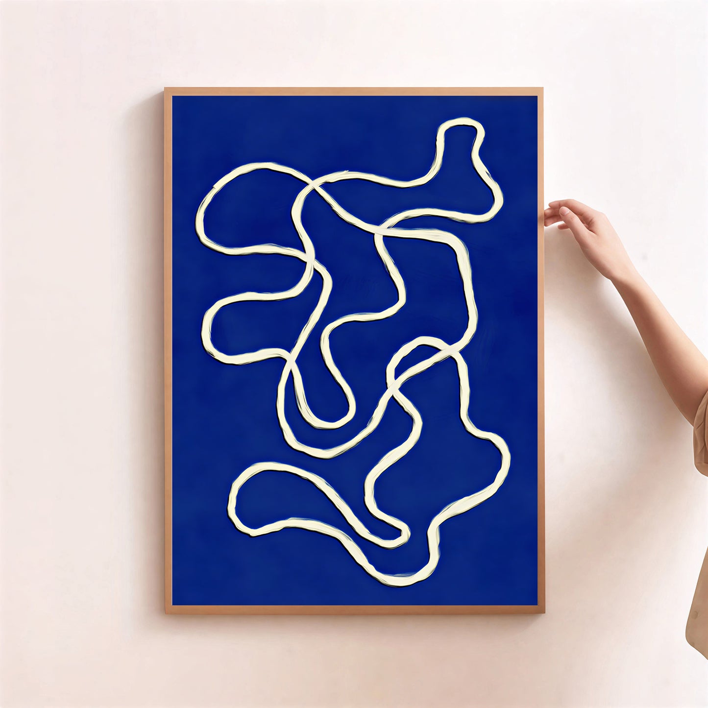 Abstract art print with white lines on a blue background, framed in a wooden border, being held by a person.