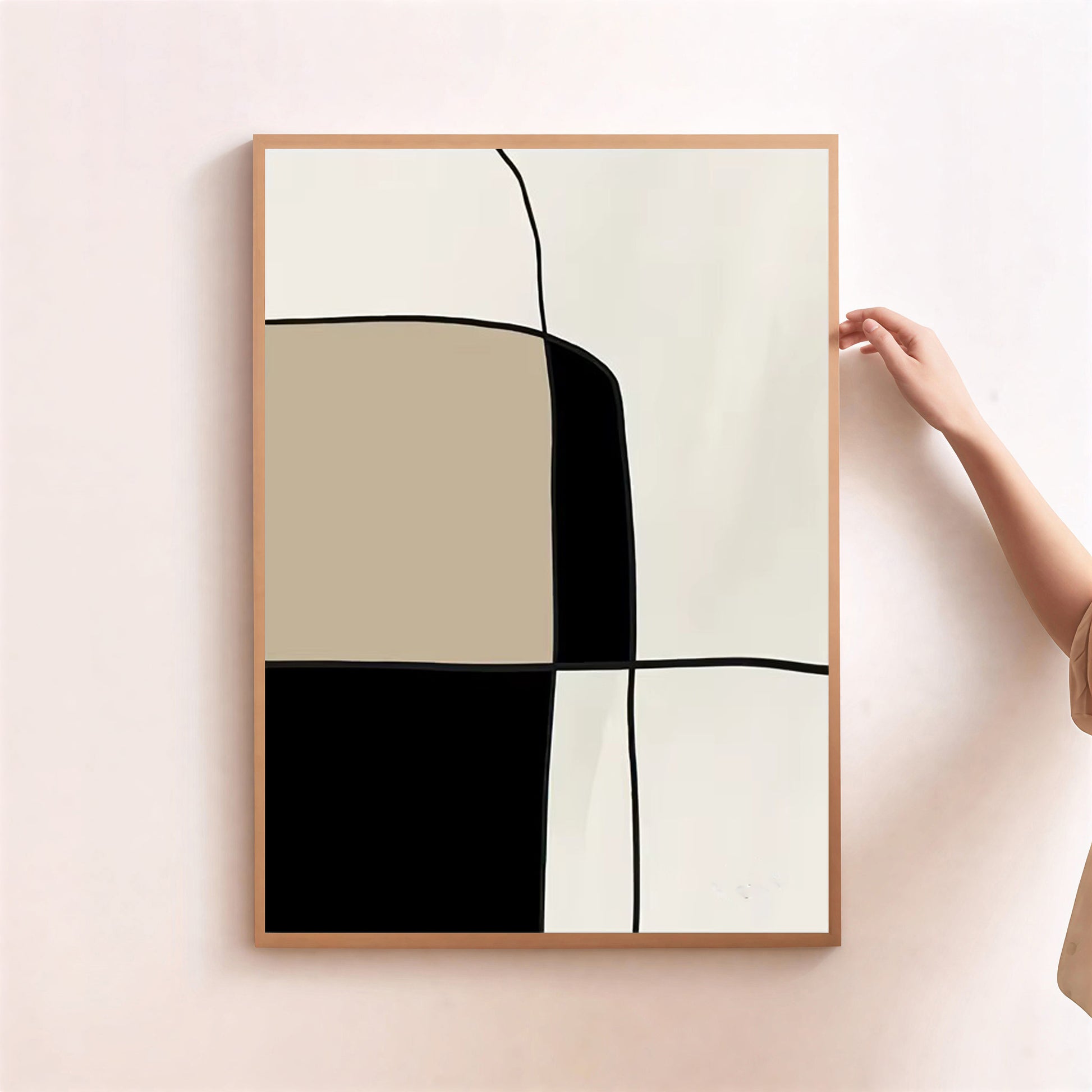 Abstract art print with geometric shapes in a wooden frame on a light pink wall.