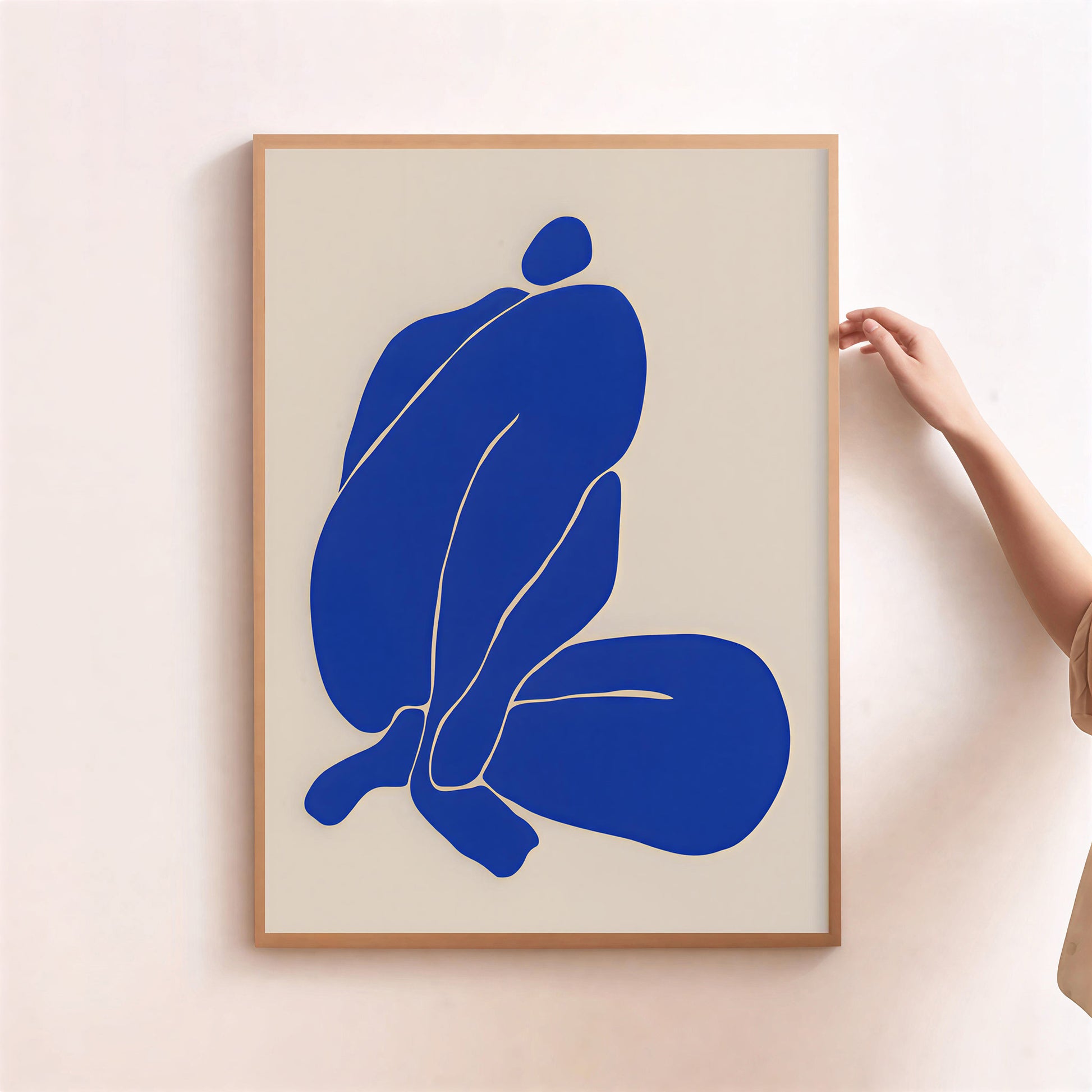 Framed abstract art print with a blue figure on a beige background