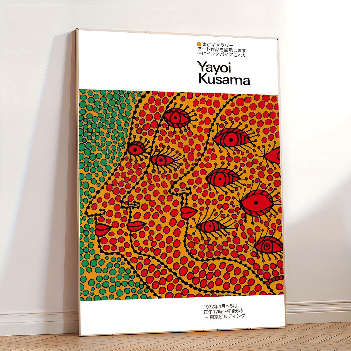 Large framed poster inspired by Yayoi Kusama leaning against a wall, displaying vivid polka-dot abstract faces in red, yellow, and green.