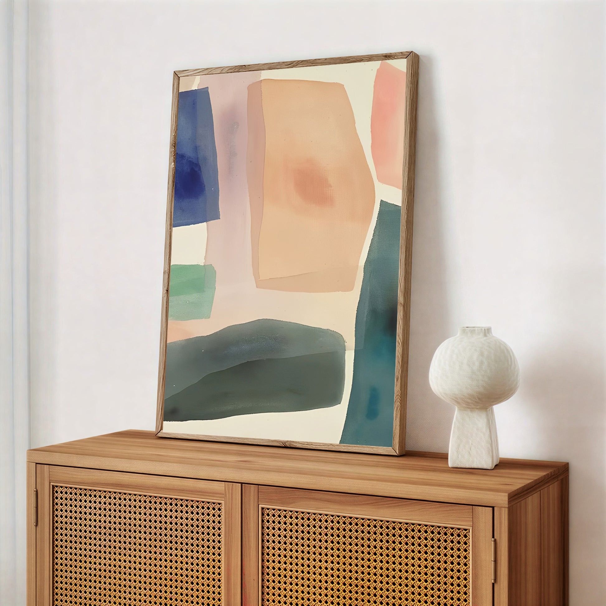 Abstract art piece on a wooden cabinet with a white vase.