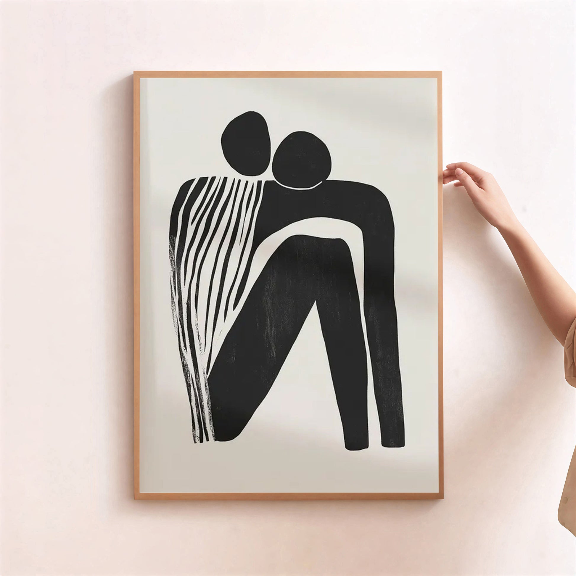 Framed abstract artwork of two figures embracing on a light background