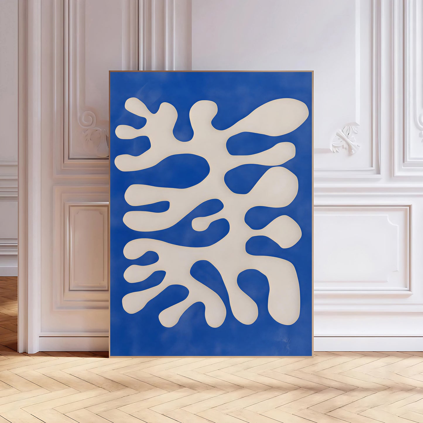 Abstract art piece with white shapes on a blue background in a room with wooden floor and white walls.