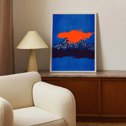 Framed abstract artwork with a blue background and orange shape on a wall above a beige armchair.