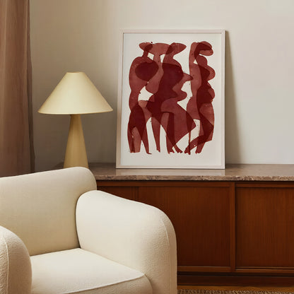 Framed abstract art on a wall above a wooden cabinet with a beige armchair and lamp.