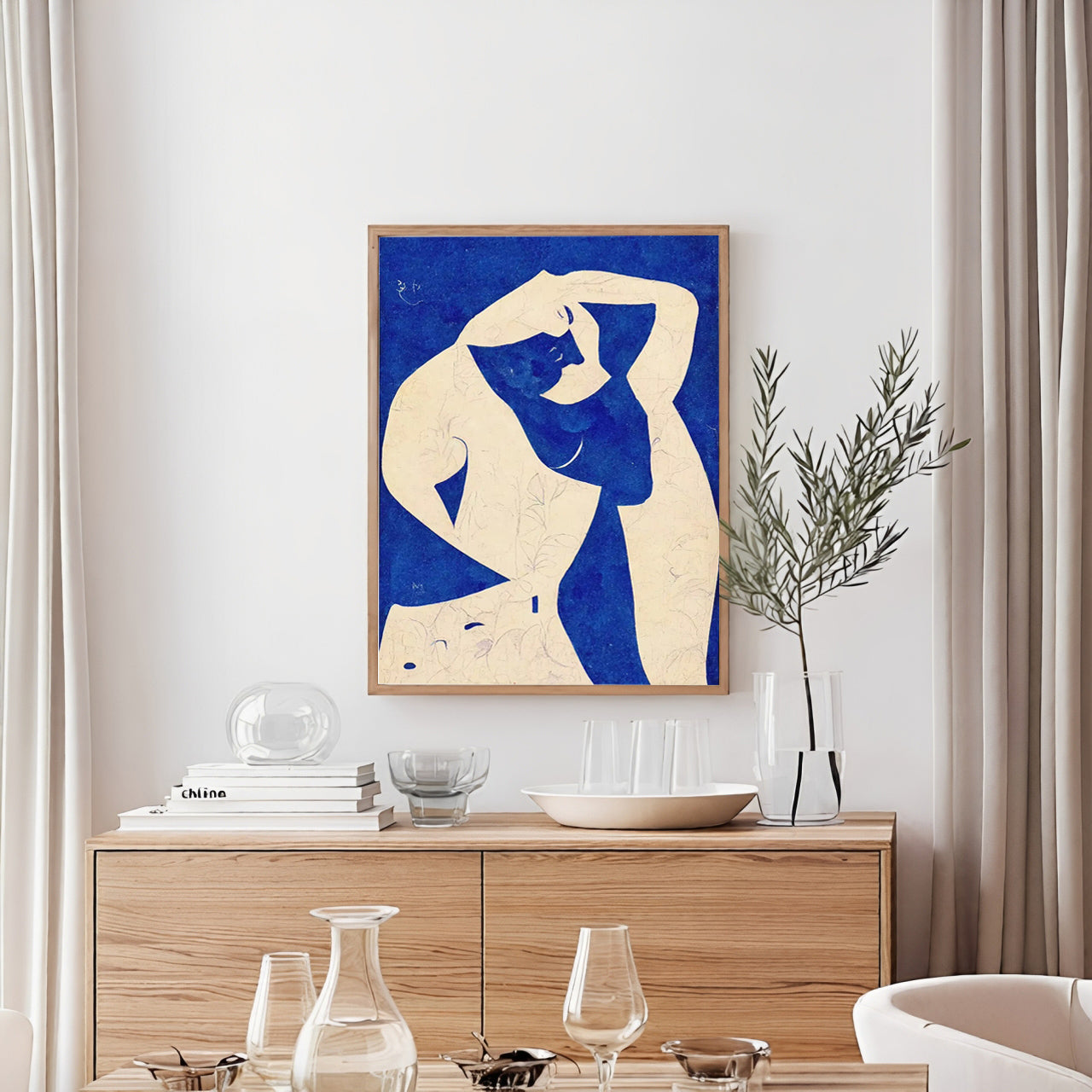 Framed abstract art of a nude figure on a wall above a wooden sideboard with decorative items.