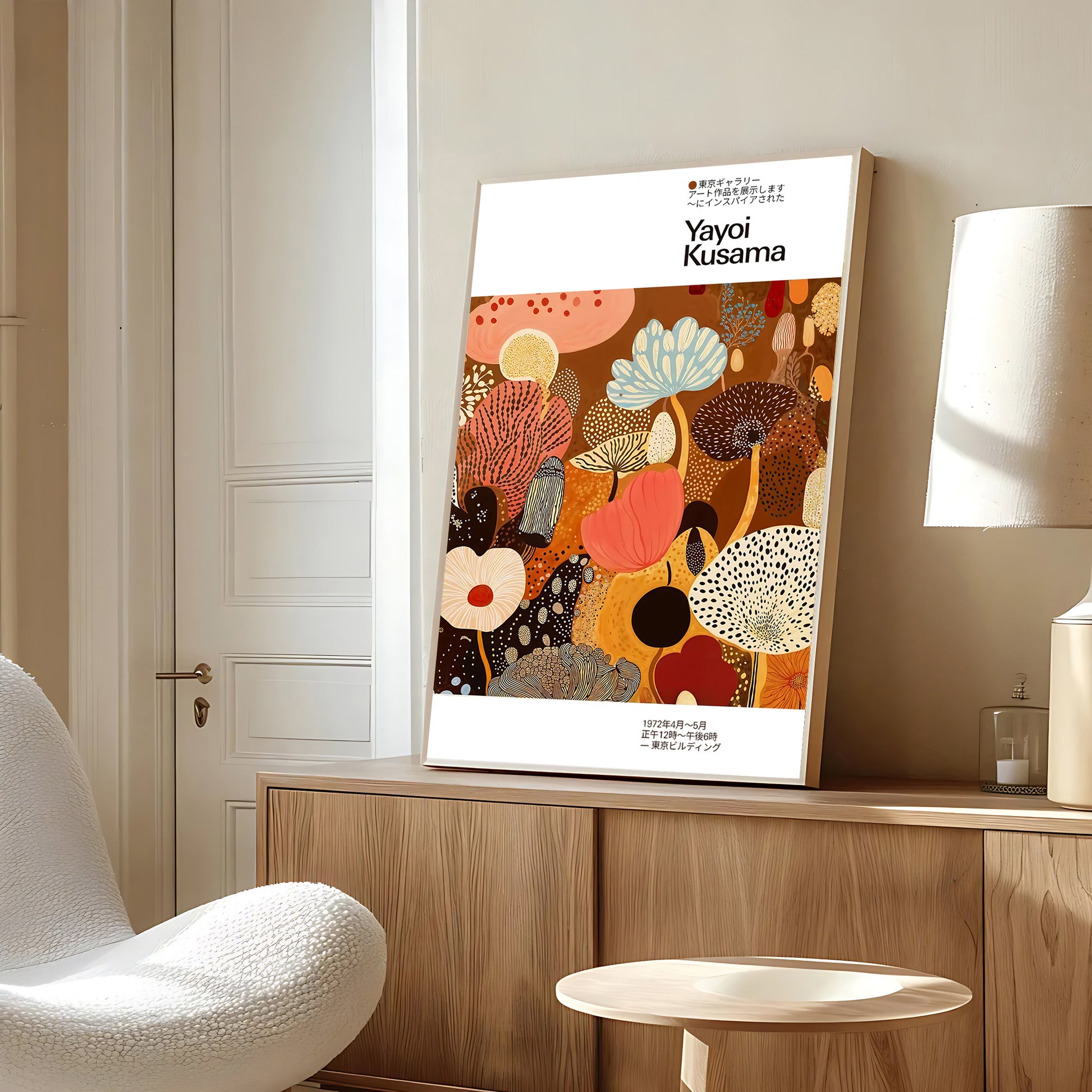 Framed artwork with 'Yayoi Kusama' on a wall in a room with a chair and lamp.