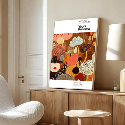 Framed artwork with 'Yayoi Kusama' on a wall in a room with a chair and lamp.