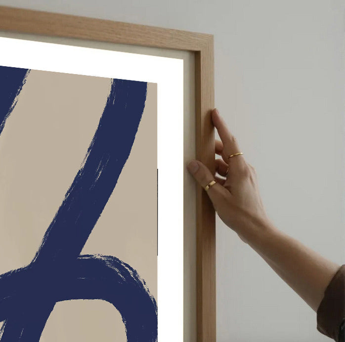 Person holding a wooden frame with Minimalist abstract navy blue wall art print on a plain wall