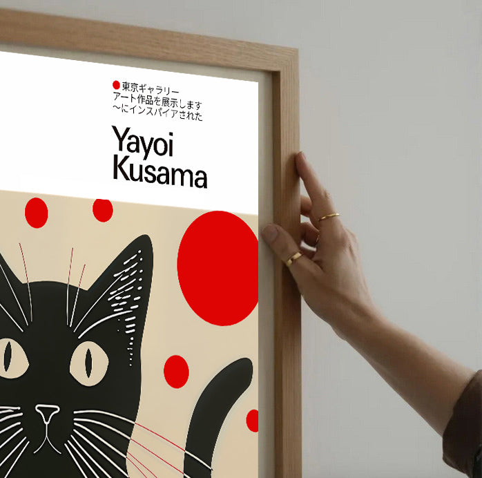 Framed artwork by Yayoi Kusama featuring a black cat with red dots on a beige background.