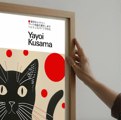Framed artwork by Yayoi Kusama featuring a black cat with red dots on a beige background.