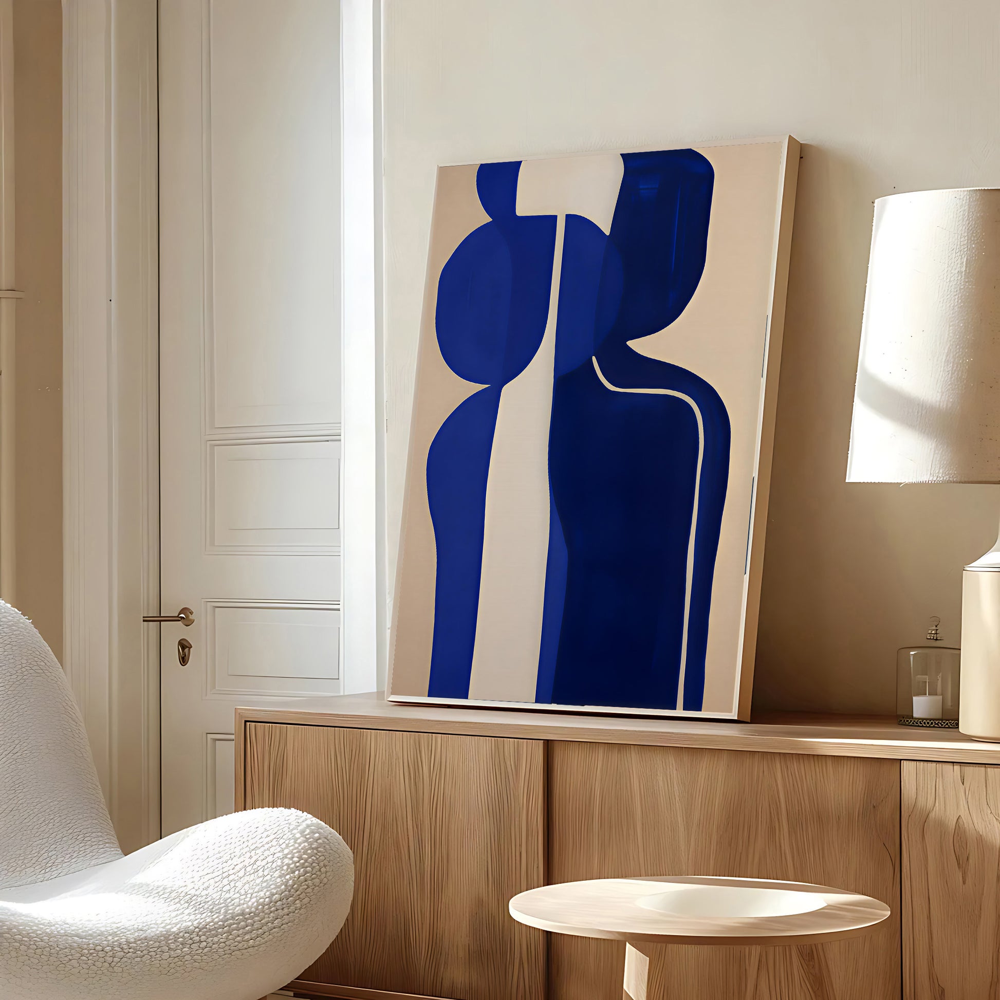Abstract blue and white artwork on a wall in a modern room with a chair and lamp.