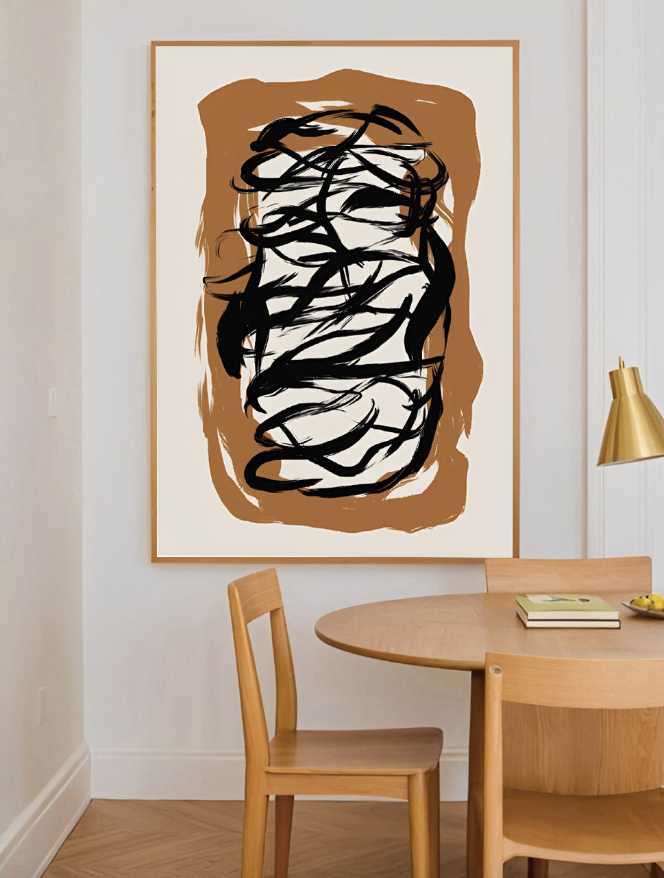 Abstract artwork in a frame on a wall above a wooden dining table with chairs.