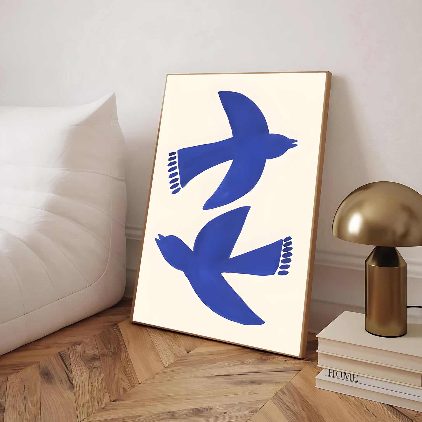 Framed artwork with blue bird design on a light background, placed on a wooden floor.
